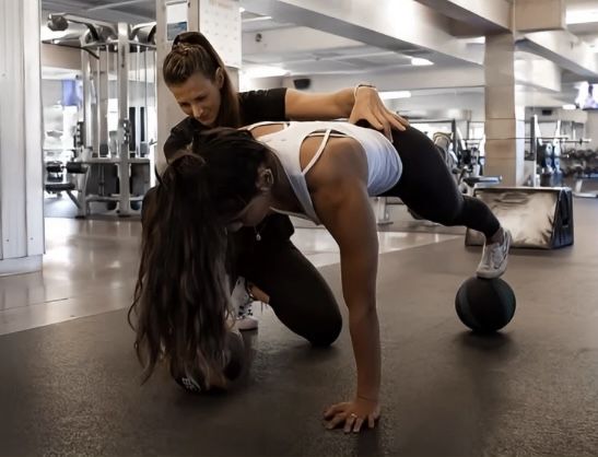 Jordanna coaching a woman through corrective strength training in a calm, light studio